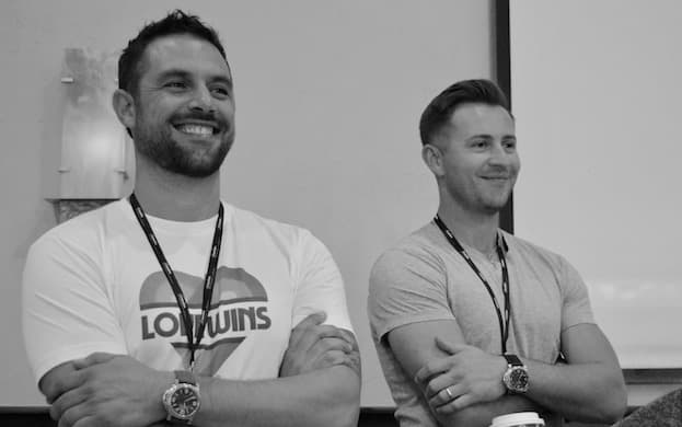 Cousins Maine Lobster founders, Jim and Sabin, smiling with their arms crossed, at a Franchisee retreat.