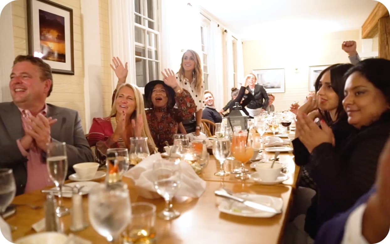 A photo of Cousins Maine Lobster family members cheering for one another at a Franchise Retreat dinner.