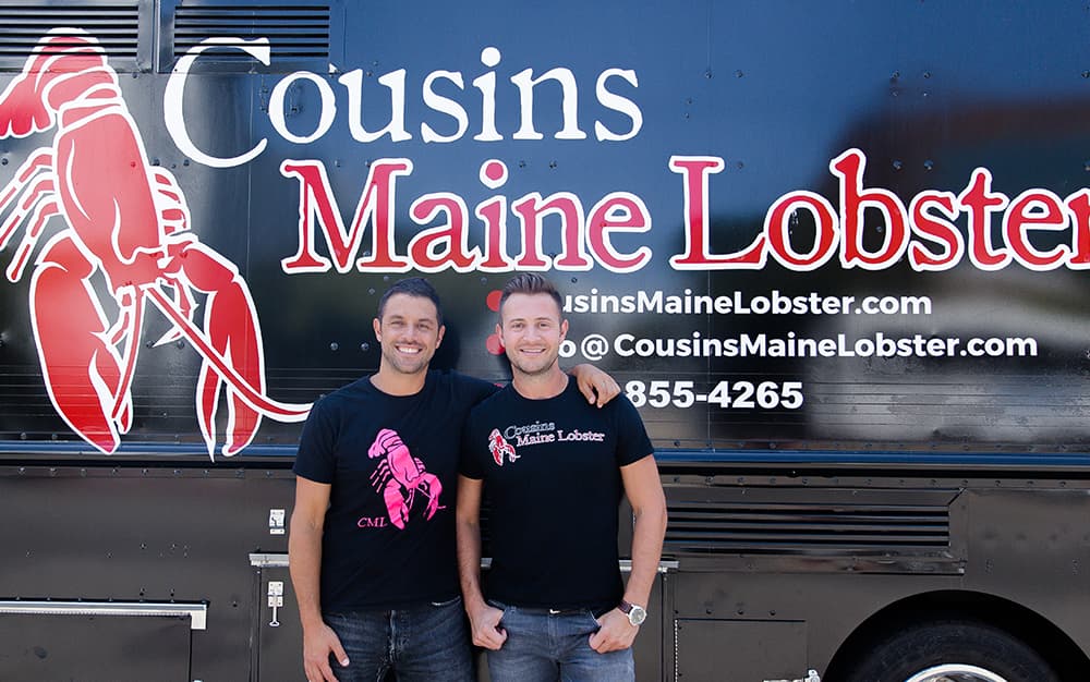 A photo of Jim & Sabin standing in front of a food truck
