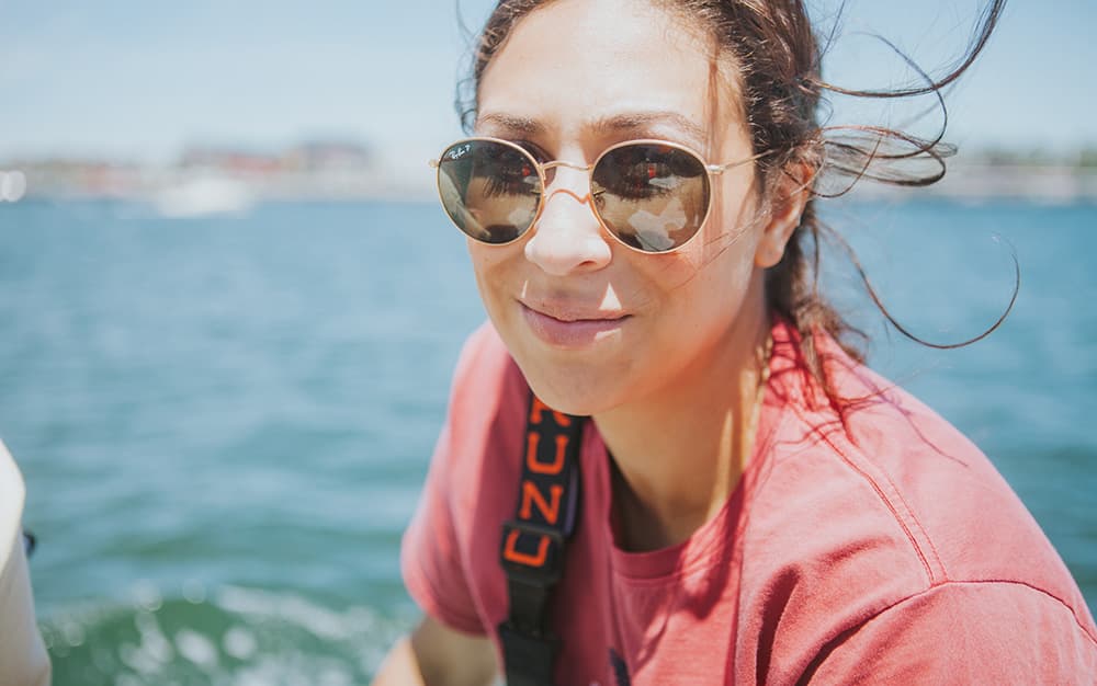 A closeup photo of one of our Trenton Philly owners in sunglasses, hair blowing in the wind, on a lobster boat in Maine.
